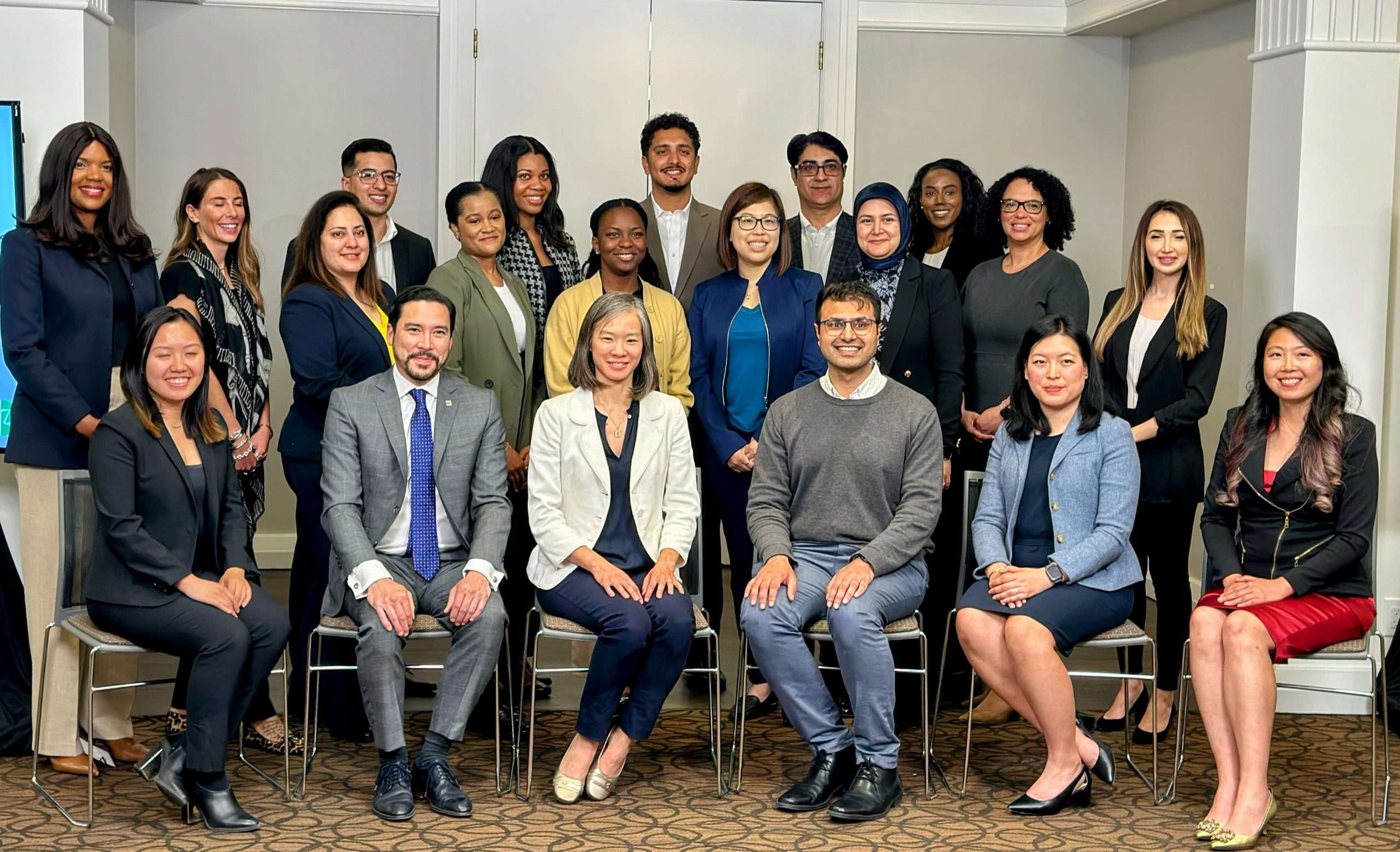 Mante stands on the far left wearing a navy blue blazer, cream pants and brown heels as she smiles amongst a group of members of the OBA Accelerator.